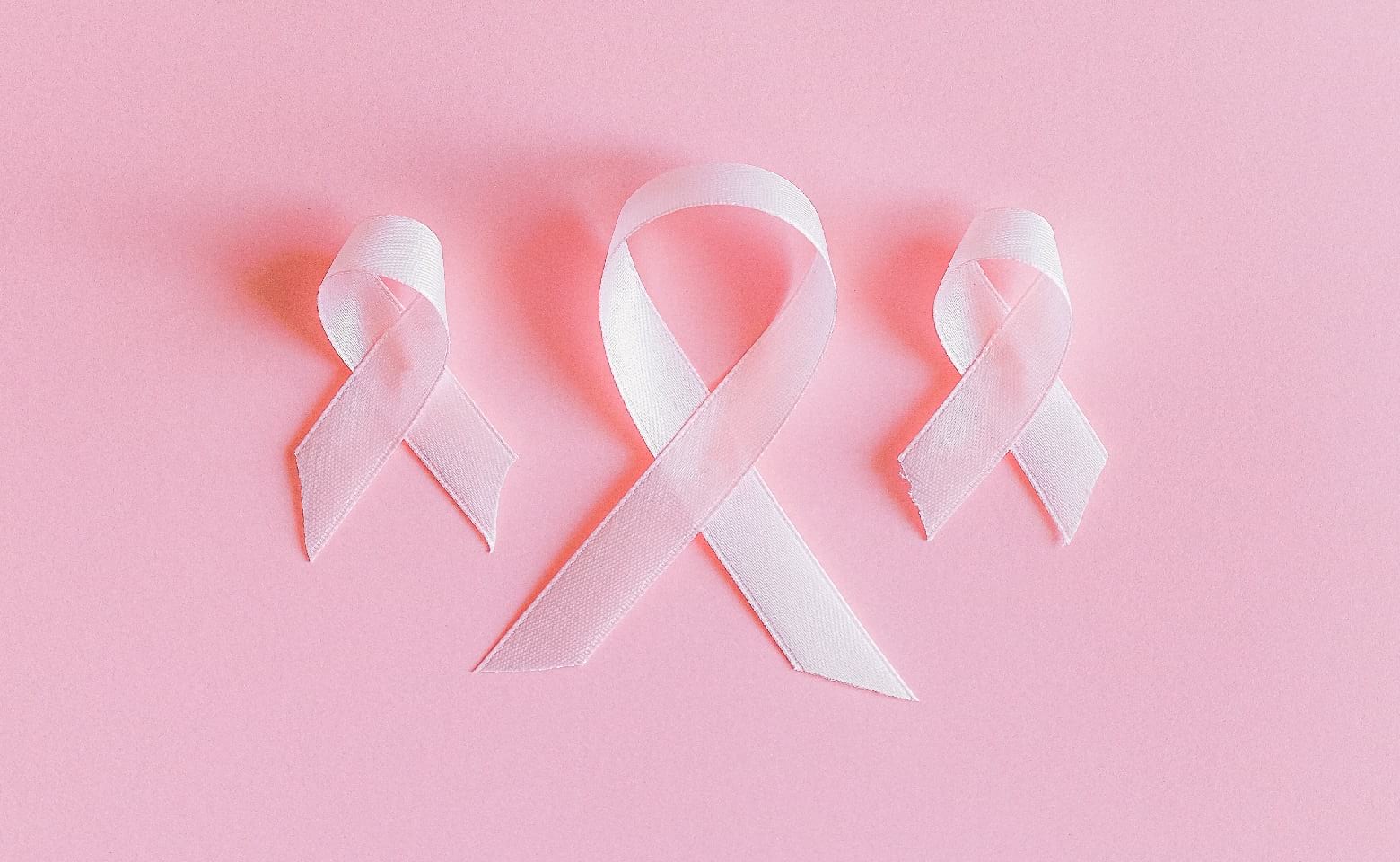 Three breast cancer ribbons on a pink background 